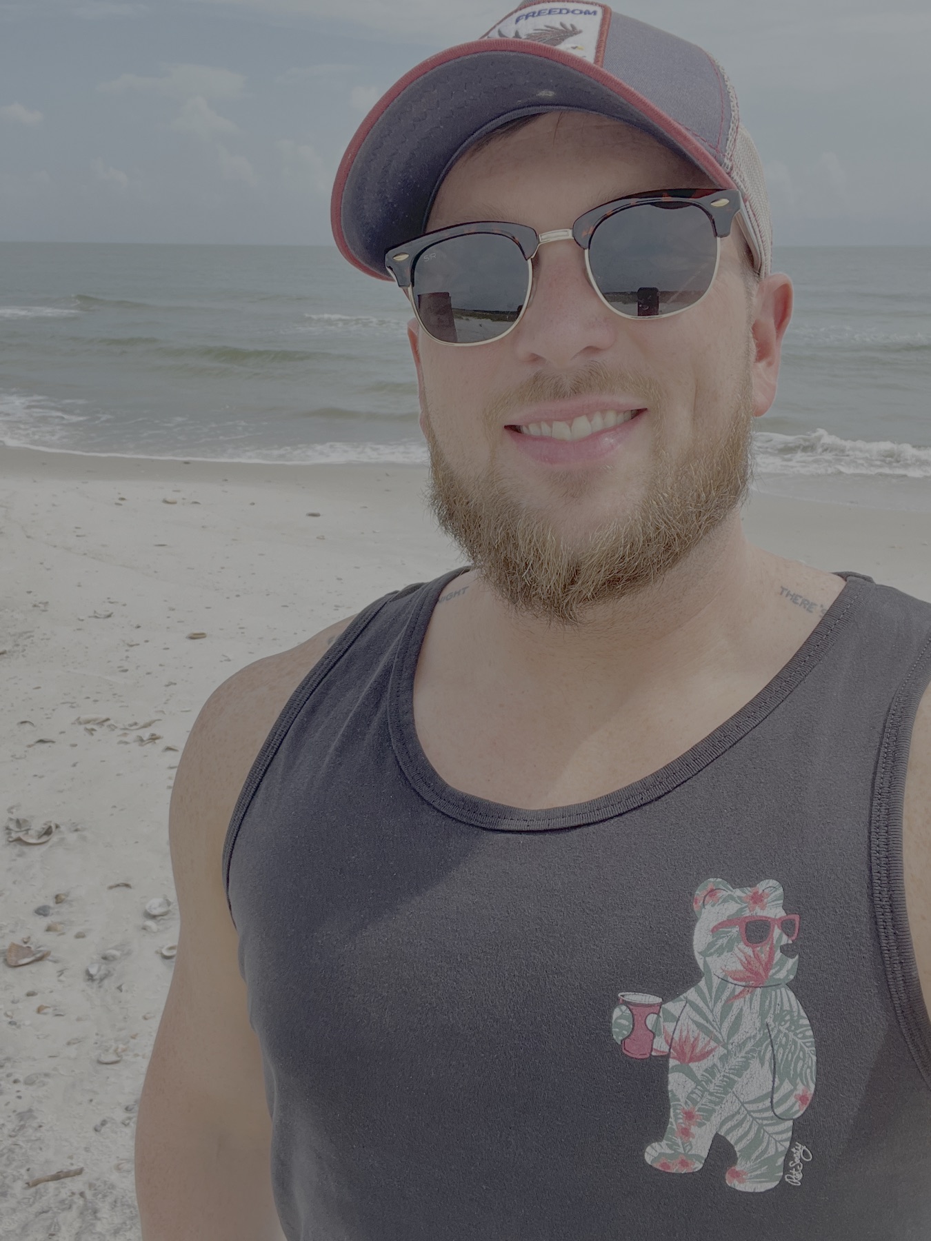 Nathan Haynes smiling on a beach beside the ocean